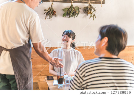 A couple ordering from a waiter at a cafe 127589939