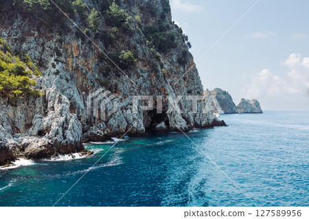 Beautiful seascape with a ship. Sea voyage. rocky shore with turquoise transparent water. Picturesque natural landscape with rough texture, Ecotourism. Fascinating seascape. Beautiful seascape with a ship. Sea voyage. rocky shore with turquoise transparent water. Picturesque natural landscape with rough texture, Ecotourism. Fascinating seascape. 127589956