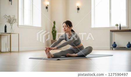Woman doing yoga by a window filled with natural light - stock photo 127590497