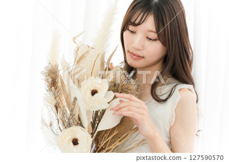 A stylish woman holding a swag of dried flowers A stylish woman holding a swag of dried flowers 127590570