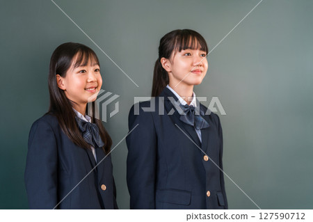 Friends in uniforms standing in front of a blackboard in a classroom, elementary school, junior high school, and high school girls Friends in uniforms standing in front of a blackboard in a classroom, elementary school, junior high school, and high school girls 127590712