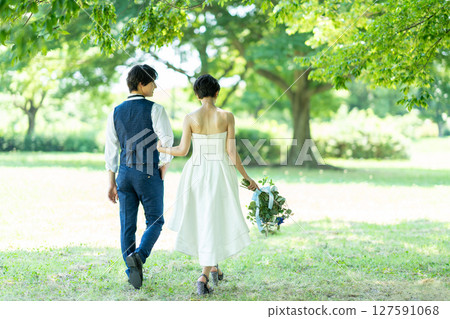 Back view of a bride and groom walking arm in arm Back view of a bride and groom walking arm in arm 127591068