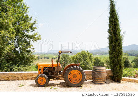 Vintage yellow tractor in countryside with barrel near countryside heels Vintage yellow tractor in countryside with barrel near countryside heels 127591580