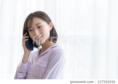 穿著睡衣的年輕女子在窗邊打電話 127592016