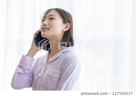 穿著睡衣的年輕女子在窗邊打電話 127592017