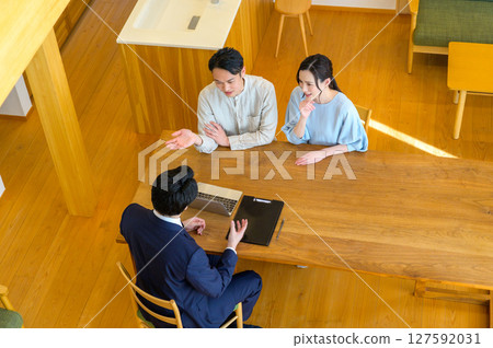 Aerial view of an office worker explaining something to a couple using a computer 127592031