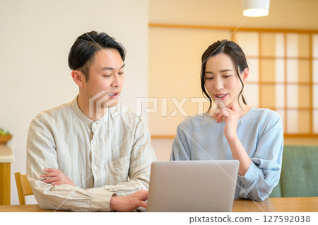 Japanese couple looking at a personal computer in the living room Japanese couple looking at a personal computer in the living room 127592038