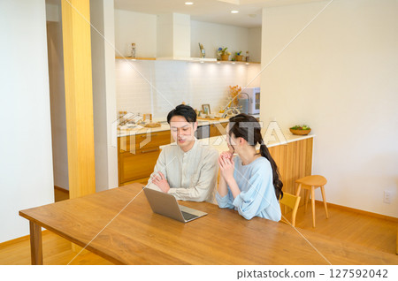 A couple looking at a personal computer in the living room 127592042