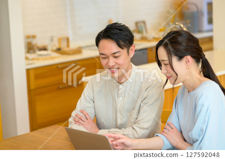 看一台個人計算機的日本夫婦在客廳 看一台個人計算機的日本夫婦在客廳 127592048
