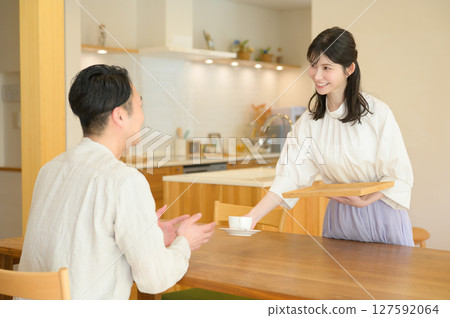 Japanese woman handing over coffee in the living room 127592064
