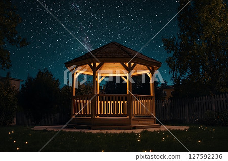 Illuminated Wooden Gazebo Under a Starry Night Sky. A tranquil scene perfect for relaxation and contemplation. 127592236