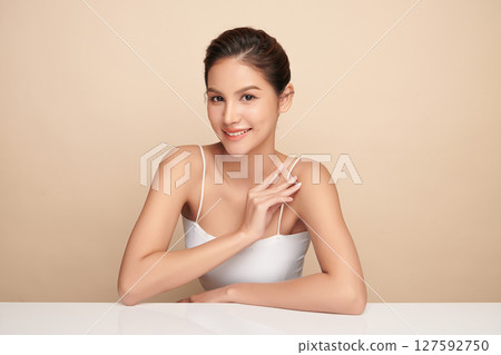 A beautiful young Asian woman with clean, fresh skin against a beige background. Skincare, facial treatment, cosmetology, beauty, and spa. An elegant portrait of an Asian woman. A beautiful young Asian woman with clean, fresh skin against a beige background. Skincare, facial treatment, cosmetology, beauty, and spa. An elegant portrait of an Asian woman. 127592750