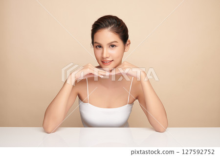 A beautiful young Asian woman with clean, fresh skin against a beige background. Skincare, facial treatment, cosmetology, beauty, and spa. An elegant portrait of an Asian woman. A beautiful young Asian woman with clean, fresh skin against a beige background. Skincare, facial treatment, cosmetology, beauty, and spa. An elegant portrait of an Asian woman. 127592752