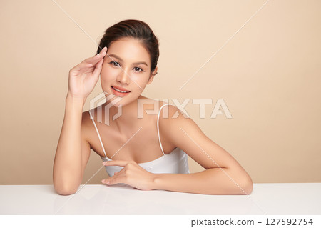 A beautiful young Asian woman with clean, fresh skin against a beige background. Skincare, facial treatment, cosmetology, beauty, and spa. An elegant portrait of an Asian woman. A beautiful young Asian woman with clean, fresh skin against a beige background. Skincare, facial treatment, cosmetology, beauty, and spa. An elegant portrait of an Asian woman. 127592754