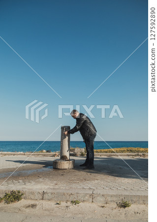 Man Washing His Hands At The Fountain Near The Sea  127592890