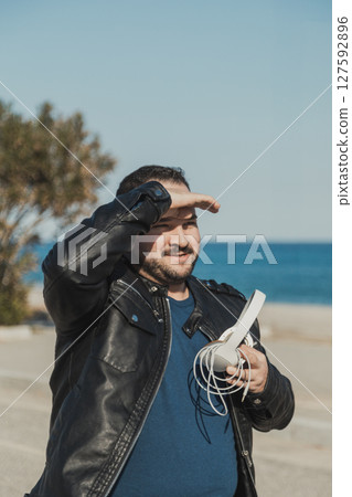 Man With Headphones In His Hands Arriving At The Sea Man With Headphones In His Hands Arriving At The Sea 127592896