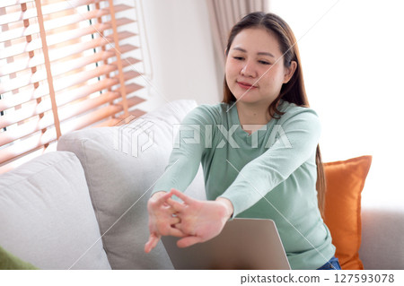 Young asian businesswoman sitting on sofa taking a break after overworked with stretching arm. Young asian businesswoman sitting on sofa taking a break after overworked with stretching arm. 127593078
