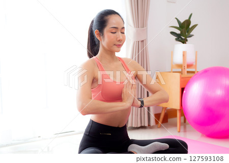 Young asian woman meditation sitting on mat in serene and tranquility with yoga in living room. 127593108