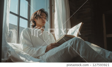 Person wear headphone sit on sofa and read book. 127593921