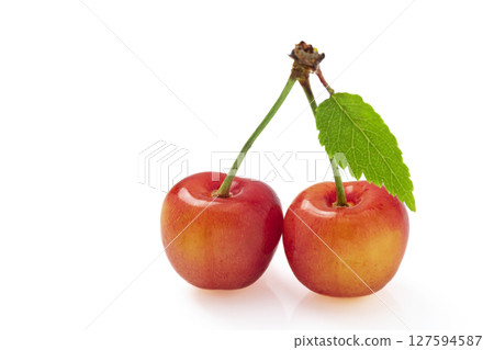 A pair of cherries with leaves on a white background 127594587