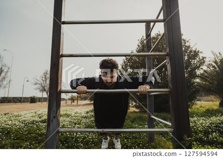 Man Works Out in Spring Outdoors Doing Push Ups Exercise Man Works Out in Spring Outdoors Doing Push Ups Exercise 127594594