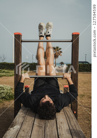 Young Man Does Intense Exercise Using City Park Structures Young Man Does Intense Exercise Using City Park Structures 127594599