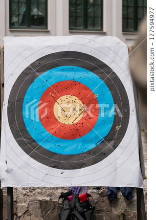 Archery Target Practice. Close-Up of a Bullseye Covered in Arrows, Outdoor Training, Sport, Red, Blue, Black, Accuracy, Wood Texture, Daylight. Archery Target Practice. Close-Up of a Bullseye Covered in Arrows, Outdoor Training, Sport, Red, Blue, Black, Accuracy, Wood Texture, Daylight. 127594977