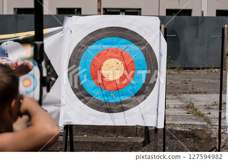 Outdoor Shooting Range Target Practice Scene with Bullet Impacts, Metal Fencing, and Sunlight, Focused Precision and Competitive Sport. Outdoor Shooting Range Target Practice Scene with Bullet Impacts, Metal Fencing, and Sunlight, Focused Precision and Competitive Sport. 127594982