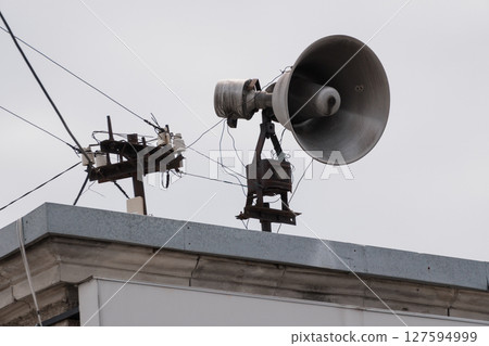 Civil Defense Siren on Rooftop: Vintage Alarm System, Metal Pole, Grey Building, Urban Decay, Communication Technology, Cloudy Sky, Detailed View 127594999