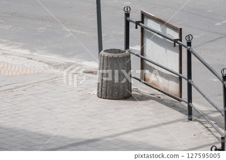 Urban Barrier with Concrete Bollard and Metal Gate in Sunlit Empty Streetscape, Gray Tones and Textured Surfaces. Urban Barrier with Concrete Bollard and Metal Gate in Sunlit Empty Streetscape, Gray Tones and Textured Surfaces. 127595005