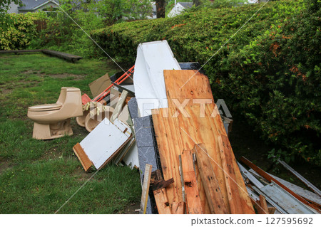 Discarded Construction Debris and an Old Toilet in a Homes Backyard 127595692