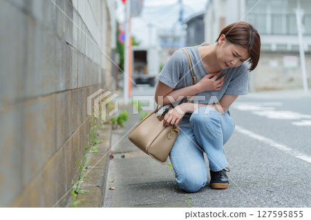 一名女子因身體狀況不佳而蹲下 一名女子因身體狀況不佳而蹲下 127595855