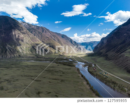 Scenic view of Chulyshman River Valley in Altai. lush green vegetation and towering mountains under cloudy sky. Travel and landscape photography. 127595935