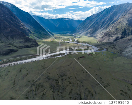 Scenic view of Chulyshman River Valley in Altai. lush green vegetation and towering mountains under cloudy sky. Travel and landscape photography. 127595940
