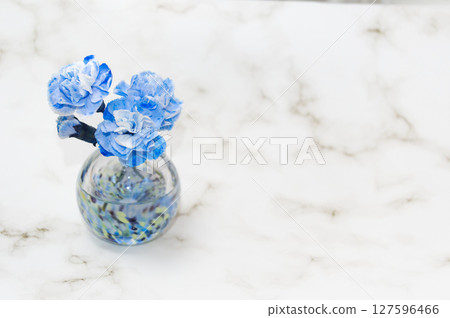 左邊是一個冷色調的花瓶，裡面插著一朵花蕾和三朵康乃馨 127596466