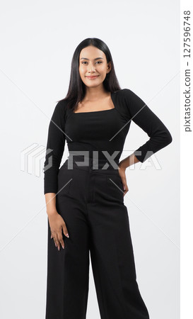 Elegant fashion model in a chic black outfit poses confidently in a studio. The woman showcases professional attire with timeless style and modern flair. ideal for fashion and lifestyle concepts 127596748