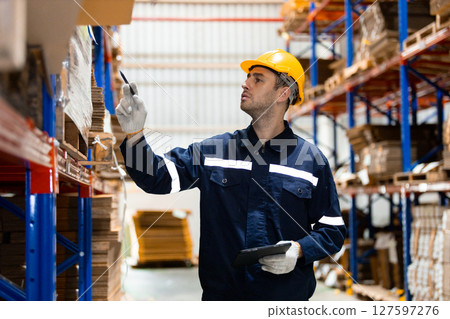 Man paper warehouse worker holding tablet checking inspecting quality cardboard corrugated carton in storage. Large industry in paper product line manufacturing. 127597276