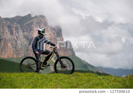 Cyclist man resting sitting on bicycle outdoors. Portrait of athlete man, rider in helmet and glasses mask looking at camera Cyclist man resting sitting on bicycle outdoors. Portrait of athlete man, rider in helmet and glasses mask looking at camera 127598610