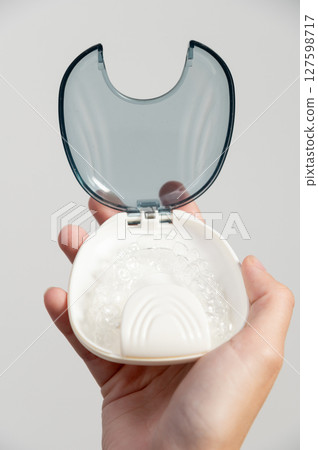 Braces. Invisible aligners. White background, close-up. Transparent aligners for teeth jaws. Transparent dental aligners on a white storage case. Prevention treatment of gums 127598717