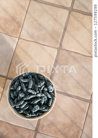 Bowl Full of Honeysuckle Berry on Tile Surface. Healthy Eating and Delicious Snack. Bowl Full of Honeysuckle Berry on Tile Surface. Healthy Eating and Delicious Snack. 127599299