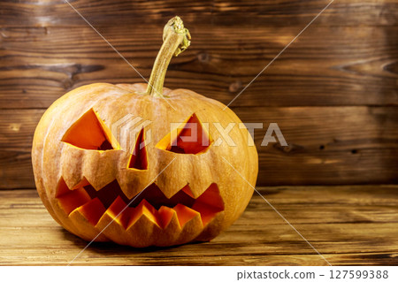 Spooky Halloween pumpkin jack-o-lantern on a wooden background Spooky Halloween pumpkin jack-o-lantern on a wooden background 127599388