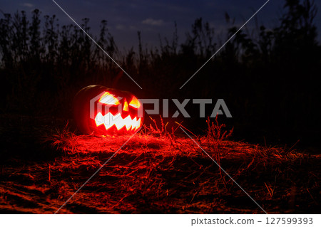 Spooky Halloween pumpkin jack-o-lantern with burning candles in scary forest at night 127599393