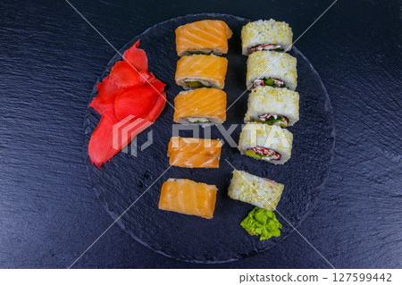 Set of sushi rolls on a black stone slate. Top view 127599442
