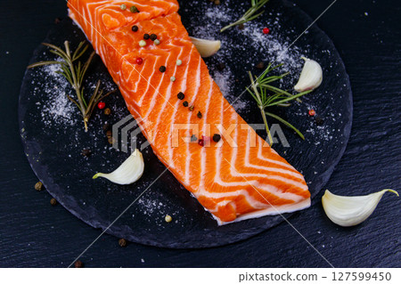 Raw salmon fillet with spices on black slate 127599450