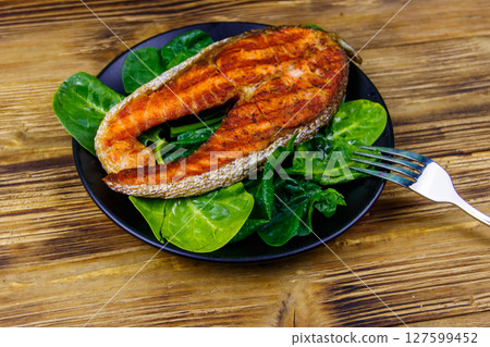 Grilled salmon steak with spinach on wooden table Grilled salmon steak with spinach on wooden table 127599452