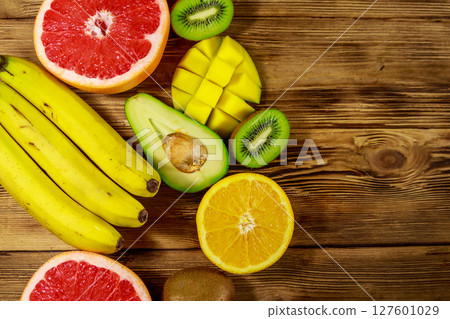 Assortment of tropical fruits on wooden table. Still life with bananas, mango, oranges, avocado, grapefruit and kiwi fruits 127601029