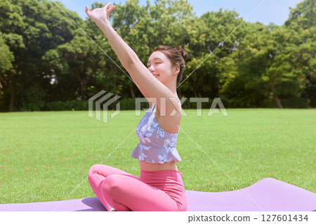 一位女士在天然草坪和藍天下，在度假氛圍中練習瑜伽和普拉提 127601434