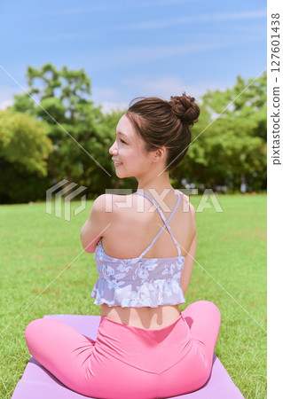 A woman doing yoga and pilates in a resort atmosphere under natural grass and blue skies A woman doing yoga and pilates in a resort atmosphere under natural grass and blue skies 127601438
