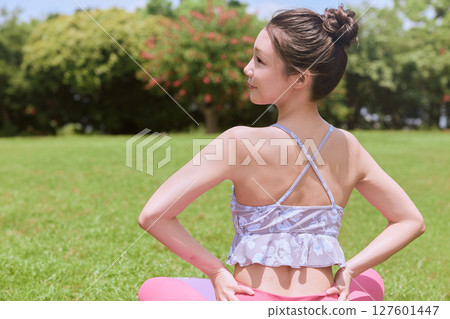 A woman doing yoga and pilates in a resort atmosphere under natural grass and blue skies A woman doing yoga and pilates in a resort atmosphere under natural grass and blue skies 127601447