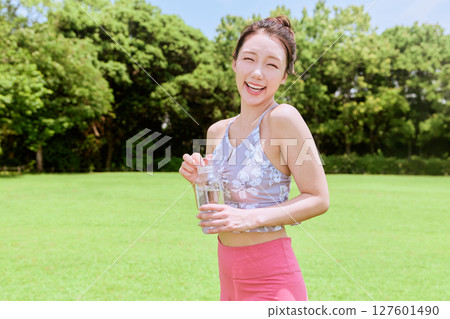 一位健康的女性在藍天下的天然草地上做完瑜伽後補充水分 127601490